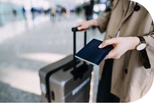 Traveler holding a passport beside luggage
